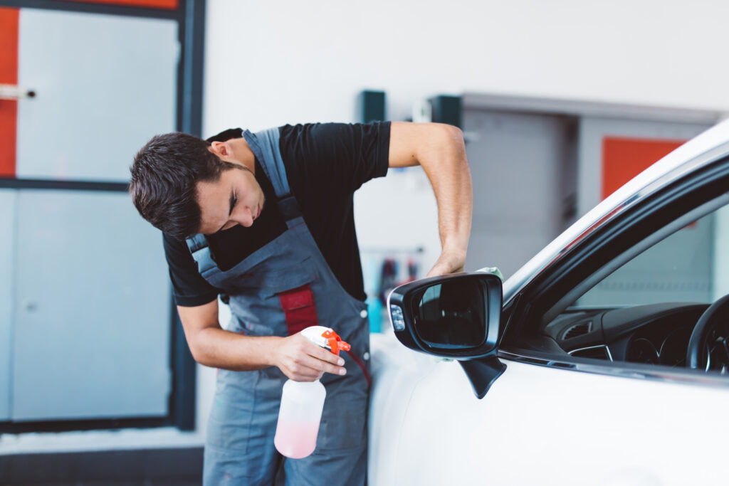 Car mechanic working to remove dent in workshop.