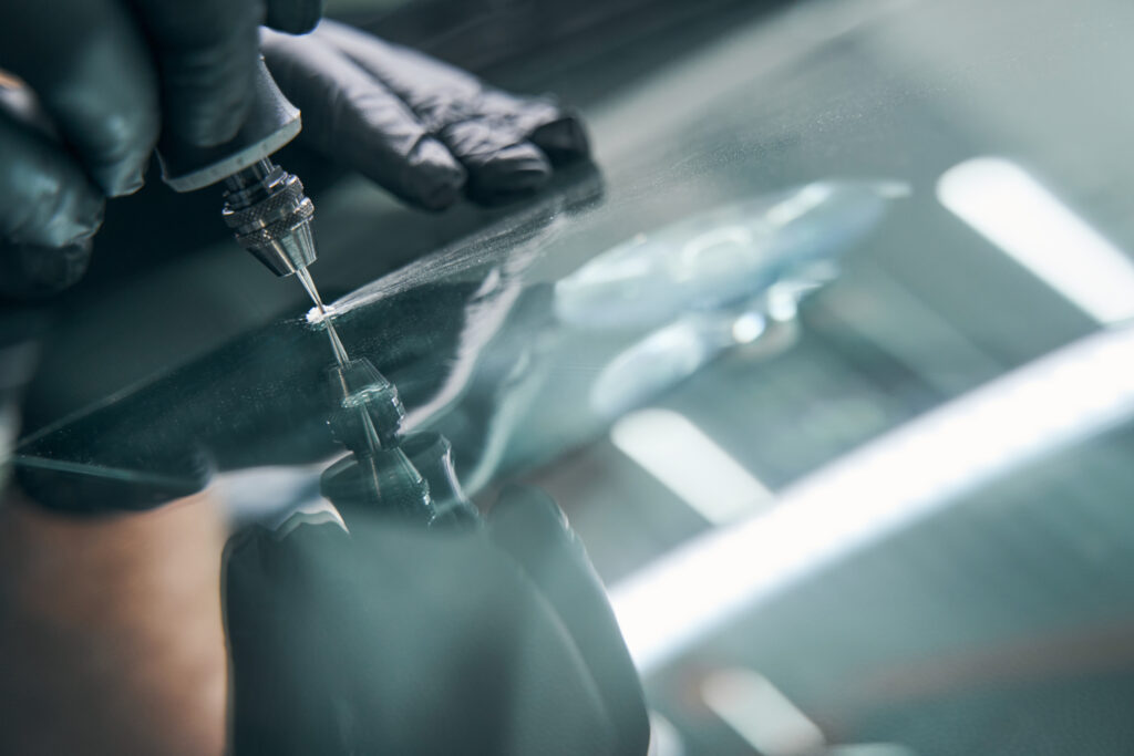 Service worker check crack on car window closeup. Windshield repair